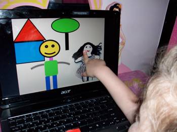A little girl points at a drawing on a computer screen